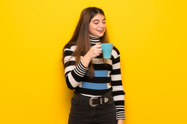 Młoda Kobieta Nad żółtą ścianą Trzyma Filiżankę Gorącej Kawy