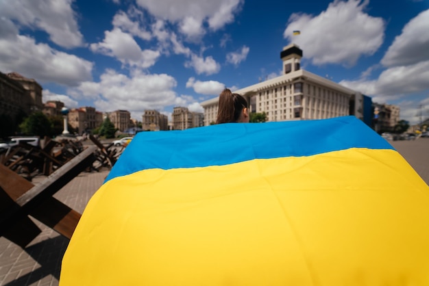 Młoda kobieta niesie za sobą powiewającą flagę Ukrainy