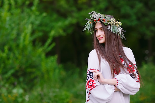 Młoda kobieta o słowiańskim wyglądzie z wieńcem z dzikich kwiatów w środku lata.