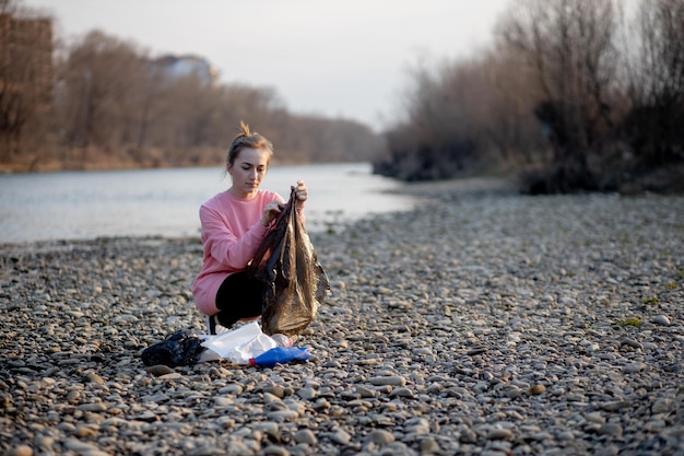 Młoda kobieta ochotniczy zbieracki śmieci na rzece