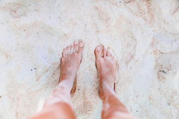 Młoda kobieta opalając się na białej plaży. Nogi