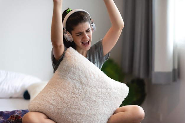 Młoda kobieta osoba nosząca słuchawki lub słuchawki do relaksu z piosenką na łóżku w sypialni w domu koncepcja szczęśliwego dźwięku słuchaj stylu życia w przytulnym odczuciu audio