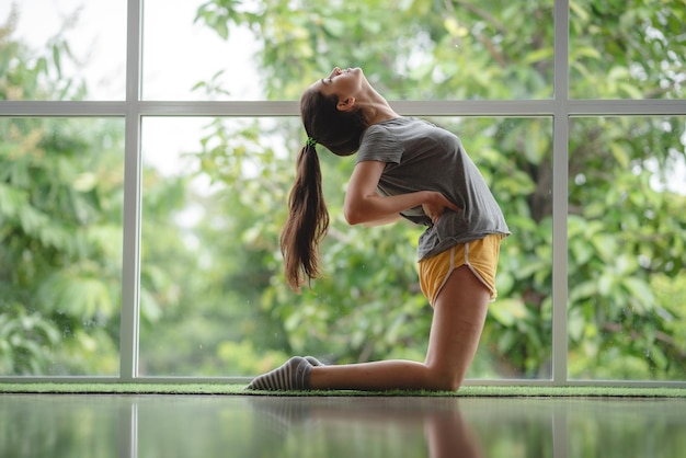 Młoda kobieta osoba uczy się jogi w domu, korzystając z wideo online szkolenia seksowna ładna dziewczyna relaksuje się ze sportem i zdalnymi ćwiczeniami fitness styl życia kryty dom na białym tle kwarantanna w domu koncepcja