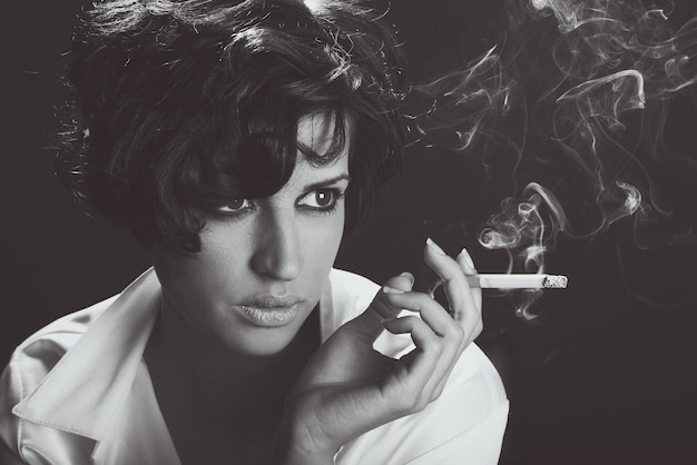 Zdjęcie młoda kobieta paląca papierosa na czarnym tle