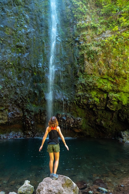 Młoda kobieta patrząca na imponujący wodospad na Levada do Caldeirao Verde Queimadas Madeira