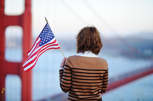 Młoda Kobieta Patrzeje Na Sławnym Golden Gate Bridge W San Fransisco Z Flaga Amerykańską, Kalifornia, Usa