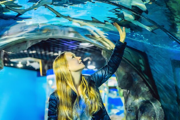 Młoda kobieta patrzy na ryby w tunelu w oceanarium