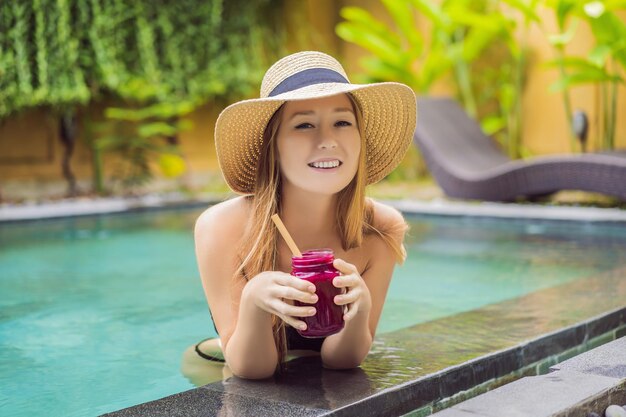 Młoda kobieta pijąca Koktajle owocowe smoka na tle basenu Koktajl owocowy koncepcja zdrowego odżywiania Zbliżenie smoothie detox z owocami smoka