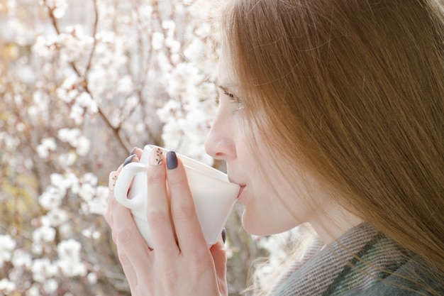 Młoda kobieta pije herbatę. Cieszyć się wiosną