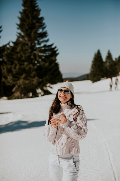 Młoda kobieta pije lemoniadę na górskiej trasie narciarskiej
