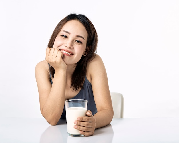 Młoda kobieta pije mleko na stole