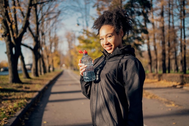 Młoda kobieta pije wodę z plastikowej butelki Wygodna kurtka sportowa Wygląd