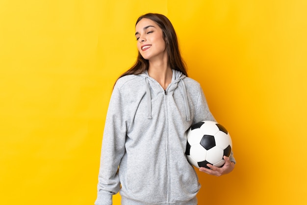 Młoda kobieta piłkarz na białym tle na żółtym tle, śmiejąc się