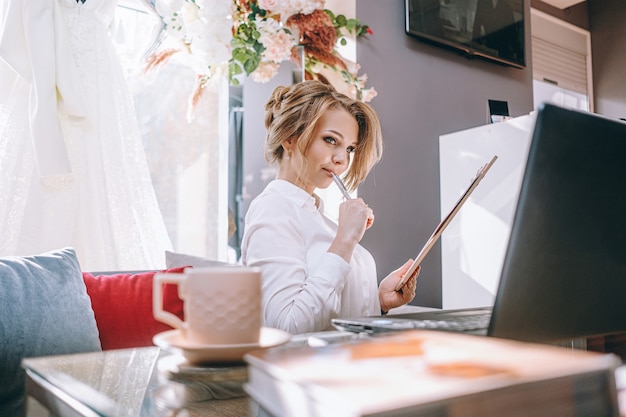 Zdjęcie młoda kobieta planowania ślubu w biurze z laptopa i tabletu do pisania