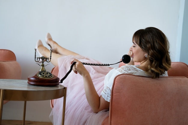 Zdjęcie młoda kobieta plus rozmiar rozmawia przez telefon retro siedzi na krześle