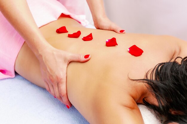 Młoda kobieta podczas masażu w spa Kobieta cieszy się relaksującym masażem pleców w salonie piękności Pielęgnacja ciała Pielęgnacja skóry