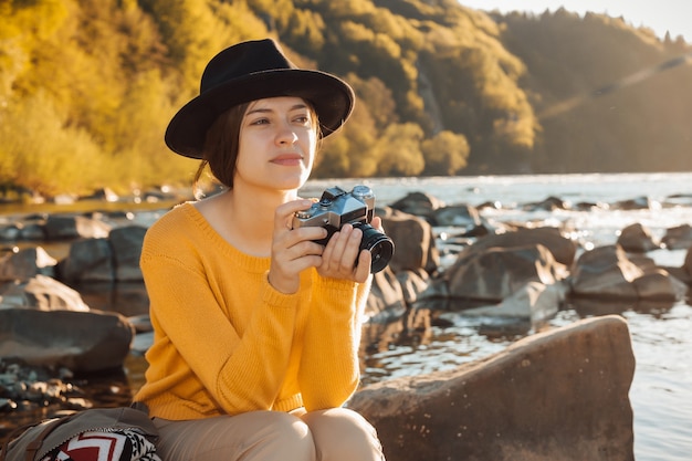 Młoda kobieta podróżnik robi zdjęcia natury na retro aparacie