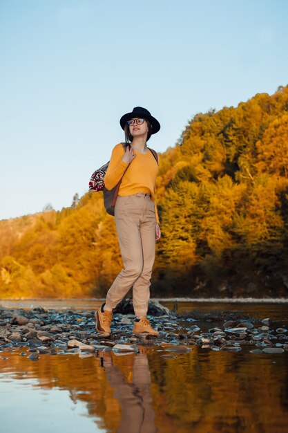 Młoda kobieta podróżnik stoi z plecakiem na tle przyrody rzeki