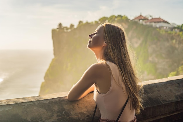 Młoda kobieta podróżnik w świątyni Pura Luhur Uluwatu, Bali, Indonezja. Niesamowity krajobraz - klif z błękitnym niebem i morzem.