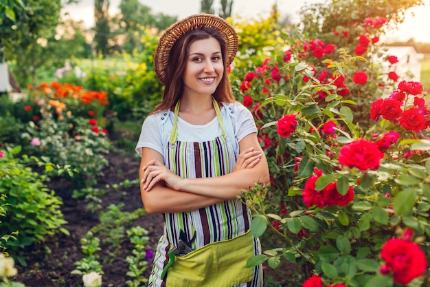 Młoda kobieta podziwiając jej letni ogród. Ogrodnik w fartuchu i kapelusz patrząc na kwiaty.