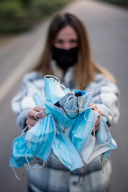 Młoda kobieta pokazuje brudne maski ochronne na zewnątrz