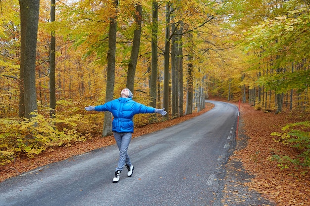 Młoda kobieta pozuje w jesiennym lesie na drodze