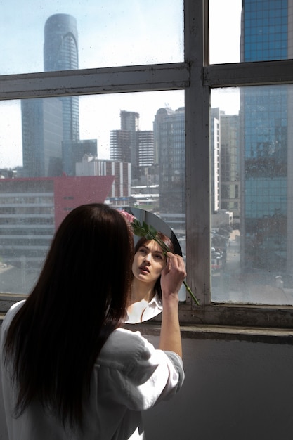 Zdjęcie młoda kobieta pozuje z lustrem w budynku obok okna