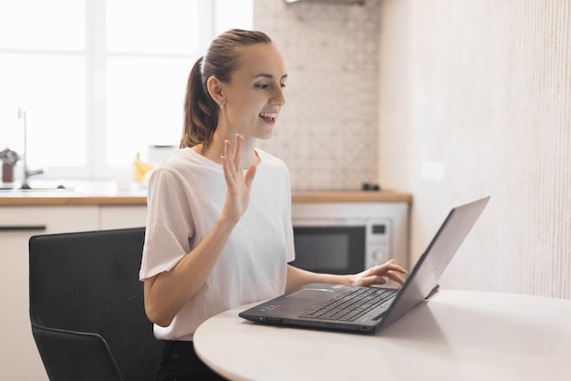 Zdjęcie młoda kobieta pracuje na laptopie w kuchni