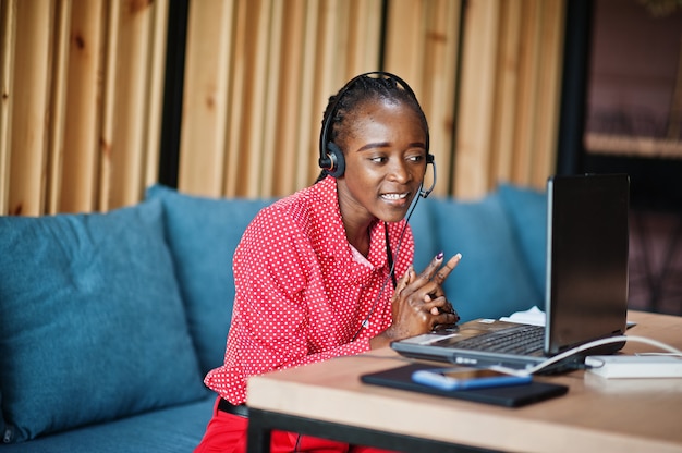 Młoda kobieta pracuje w call center operatora i agenta obsługi klienta w zestawach słuchawkowych z mikrofonem pracującym na laptopie