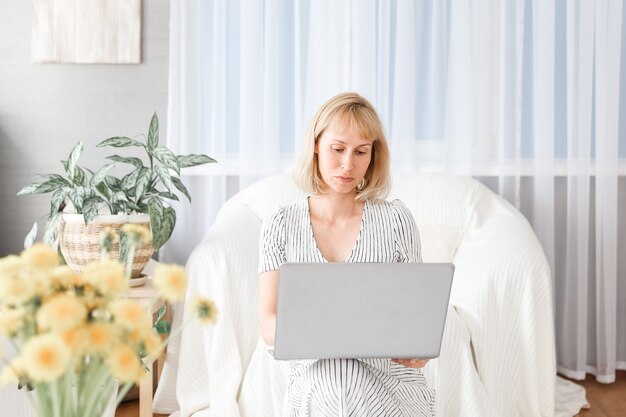 Młoda kobieta pracuje w domowym biurze. Freelancer korzystający z laptopa, telefonu i Internetu.