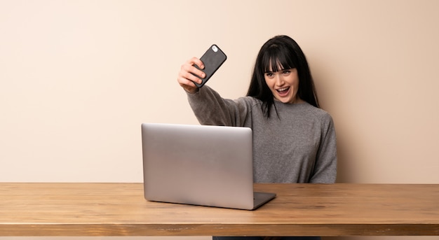 Młoda kobieta pracuje z jej laptopem robi selfie