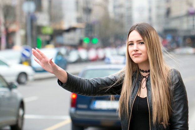 Młoda kobieta próbuje złapać taksówkę