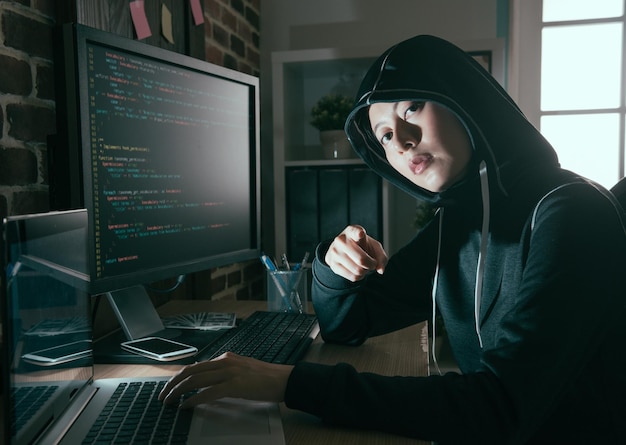 młoda kobieta programista komputerowy jako haker robi nielegalnej pracy online i patrząc na kamery wskazujące pokazano koncepcję zagrożenia.