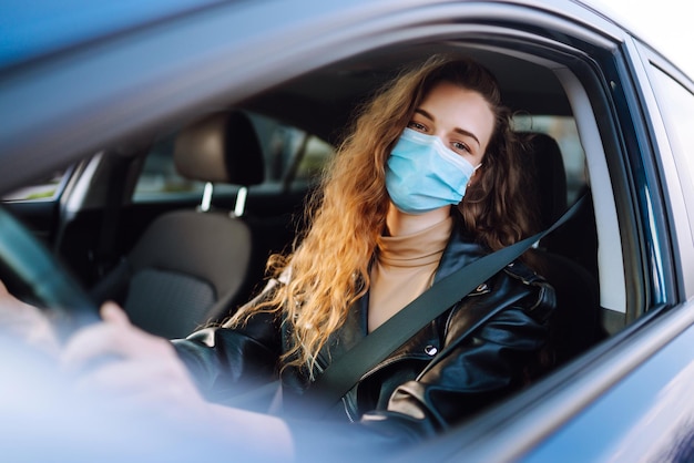 Młoda kobieta prowadząca samochód w masce medycznej podczas epidemii Izolacja transportowa Covid2019
