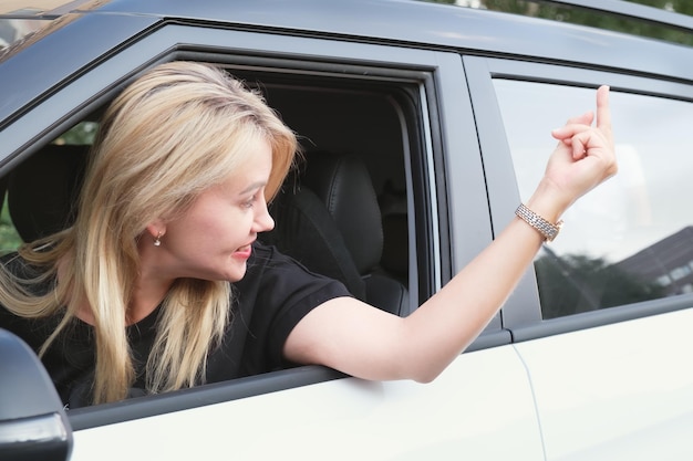 Młoda kobieta prowadząca samochód wystawiła głowę przez okno i pokazała środkowy palec