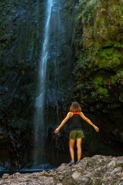 Młoda kobieta przy imponującym wodospadzie na Levada do Caldeirao Verde Queimadas Madeira