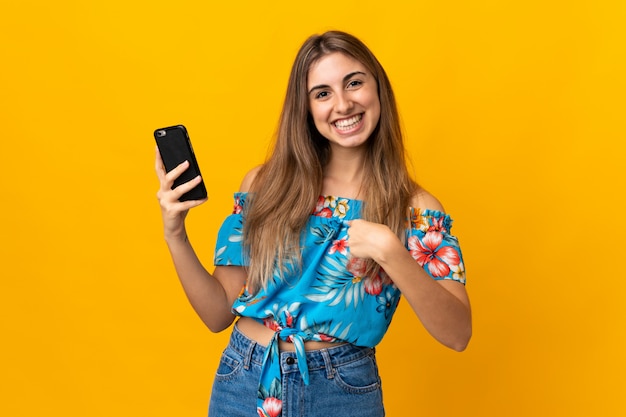 Młoda Kobieta Przy Użyciu Telefonu Komórkowego Na Na Białym Tle żółty Z Zaskoczeniem Wyraz Twarzy