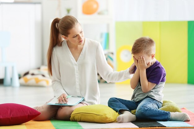 Zdjęcie młoda kobieta psycholog pracuje z małym chłopcem w biurze