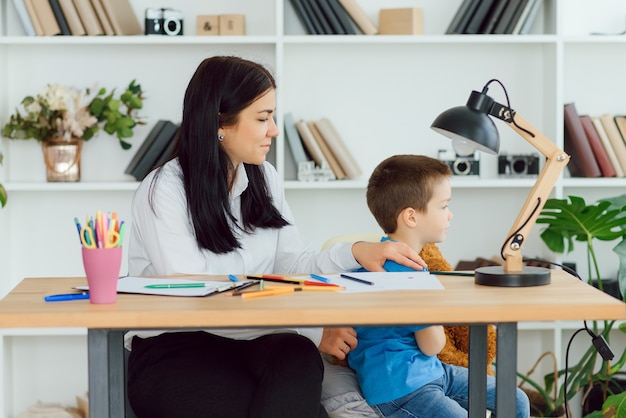 Młoda kobieta psycholog pracuje z małym dzieckiem w biurze