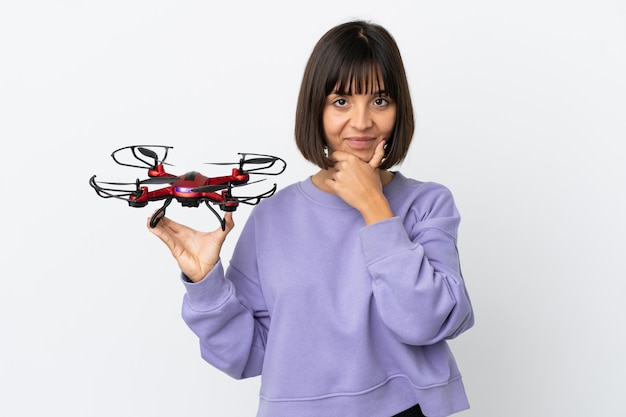 Młoda kobieta rasy mieszanej trzymająca drona na białym tle myślenia