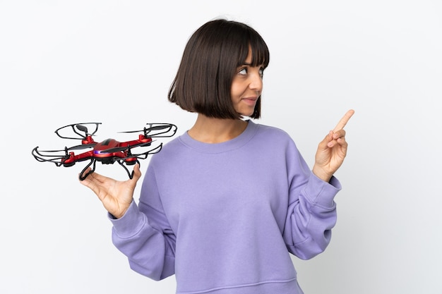 Młoda kobieta rasy mieszanej trzymająca drona na białym tle wskazująca świetny pomysł