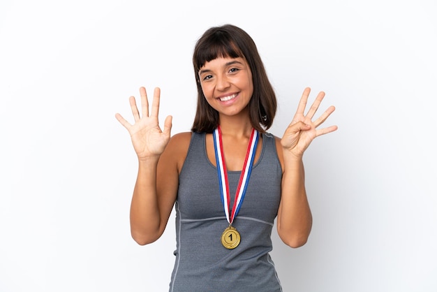 Młoda kobieta rasy mieszanej z medalami na białym tle, licząc dziewięć palcami