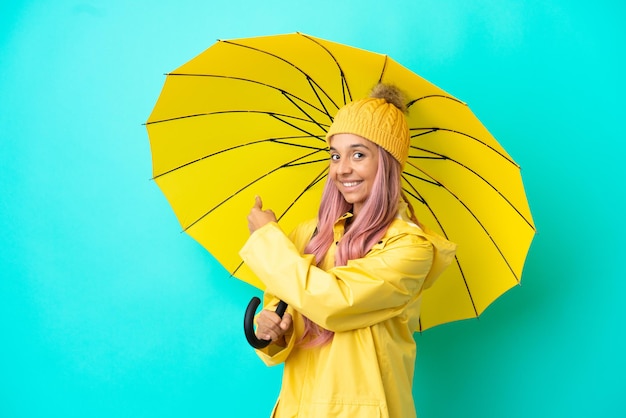 Młoda kobieta rasy mieszanej z płaszczem przeciwdeszczowym i parasolem skierowanym do tyłu
