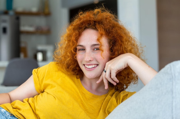 Młoda kobieta relaksuje się na kanapie Portret pięknej kobiety uśmiecha się do domu Kobieta w swobodnym patrzeniu na kamerę z kopią przestrzeni