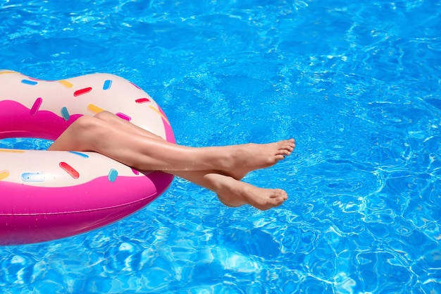 Młoda kobieta relaksuje się na nadmuchiwanym pączku w basenie