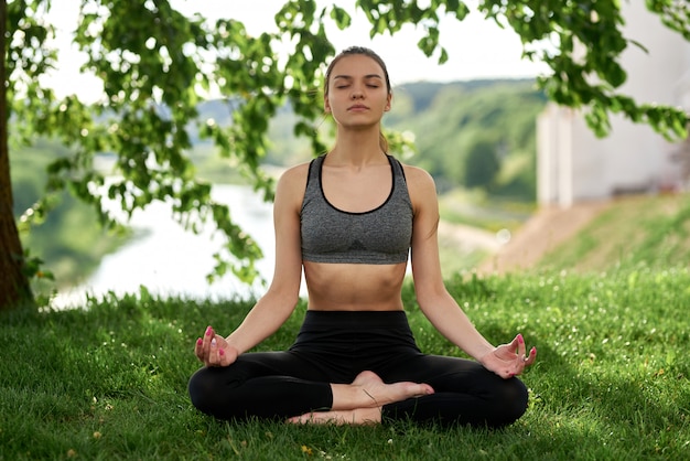 Młoda kobieta relaksuje w joga pozie na naturze w parku