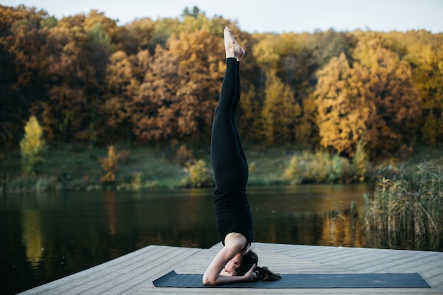 Młoda kobieta robi asan jogi w przyrodzie w pobliżu jeziora