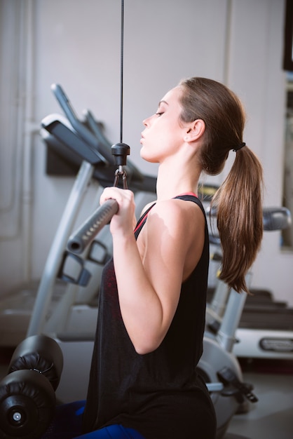 Młoda kobieta robi ćwiczeniom na maszynie przy gym