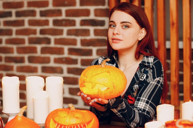 Młoda kobieta robi Halloweenowej dyni Jack-o-lantern. Kobiece ręce cięcia dyni nożem.