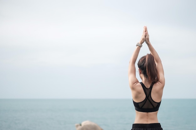 Młoda kobieta robi joga i rozciąganie mięśni rano, zdrowa dziewczyna medytacja przed widokiem na ocean. koncepcje wellness, fitness, witalności, ćwiczeń i równowagi między życiem zawodowym i prywatnym